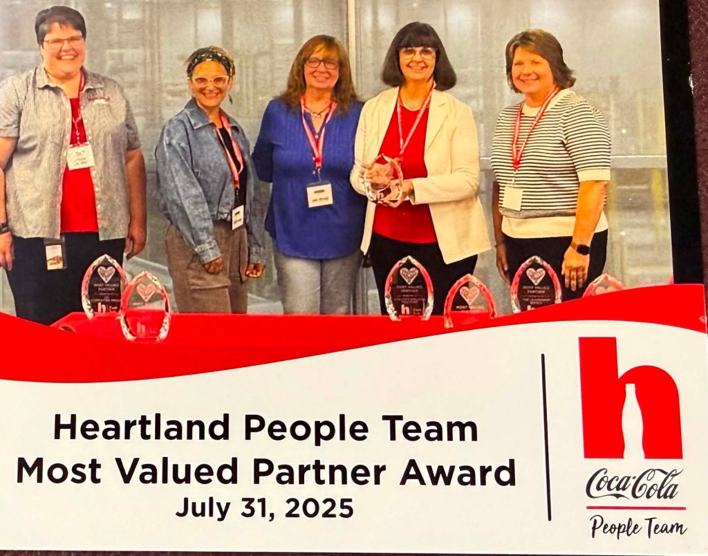 Five members of the Heartland People Team holding glass trophies, above a caption reading Heartland People Team, Most Valued Partner Award, July 31, 2025